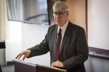 Man standing at lectern giving a talk to students in a classroom