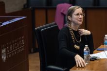 A woman sitting at a desk addressing an audience (not pictured)