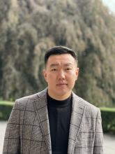 Geser Ganbaatar in a grey suit standing outside