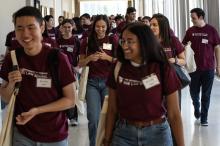 Students wearing maroon t-shirts smiling while walking down a hallway.