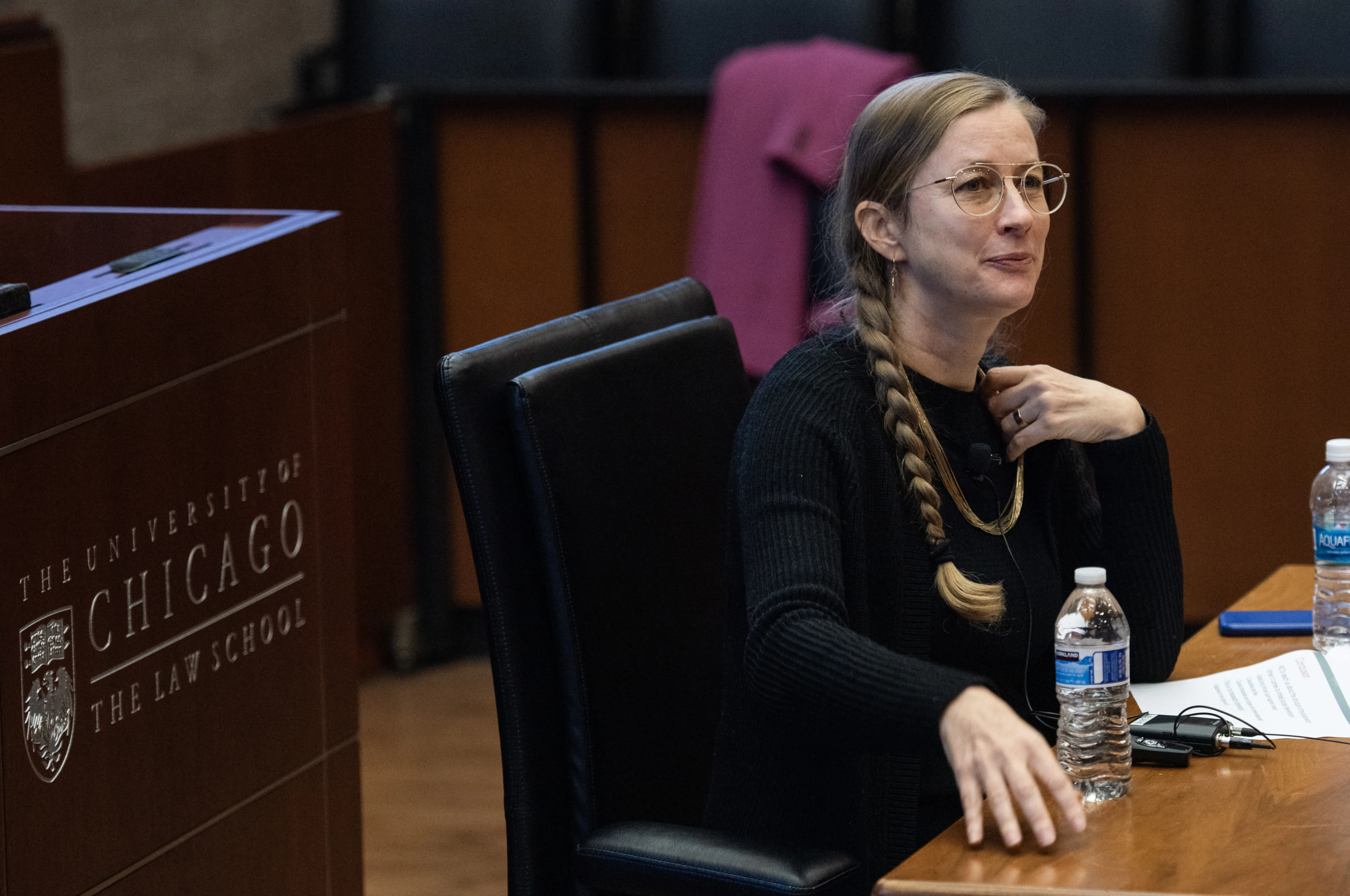 A woman sitting at a desk addressing an audience (not pictured)