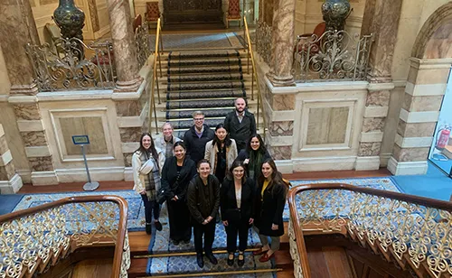 A group of people stand on an ornate staircase, posing for the camera.